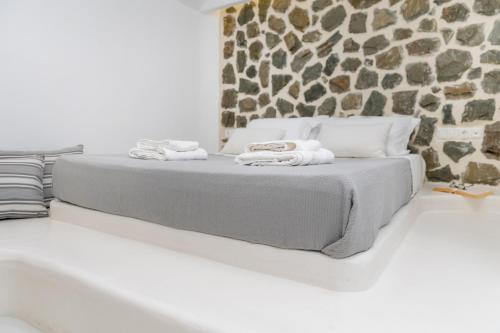 a bed in a room with a stone wall at Krina Mare Boutique Hotel in Naxos Chora