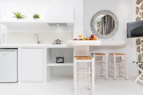 a white kitchen with a sink and stools at Krina Mare Boutique Hotel in Naxos Chora