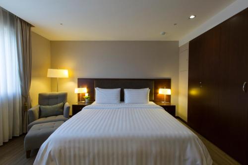 a hotel room with a large bed and a chair at CHECK inn Taipei Neihu in Taipei