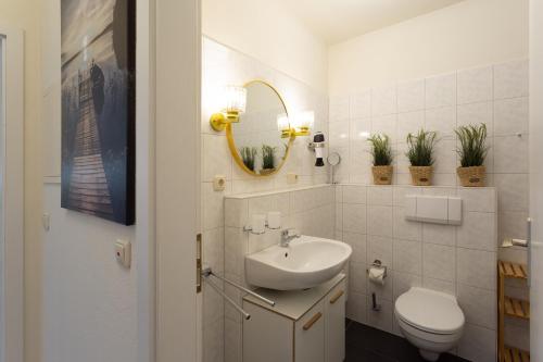 ein Badezimmer mit Waschbecken, Toilette und Spiegel in der Unterkunft Ankerplatz - Binzer Sterne in Binz