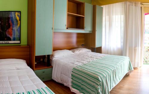 a bedroom with two beds and a cabinet and a tv at Hotel Villa Roma in Caorle