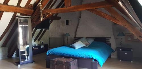 - une chambre mansardée avec un lit bleu dans l'établissement Moulin du 18ème siècle entièrement rénové, à Montapas