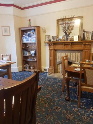 ein Wohnzimmer mit einem Kamin, einem Tisch und Stühlen in der Unterkunft Cedar Villa Guest House in Inverness