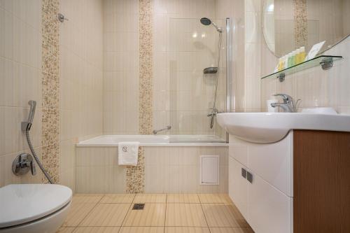 Greguar Hotel by UHM في كييف: حمام مع حوض وحوض استحمام ومرحاض