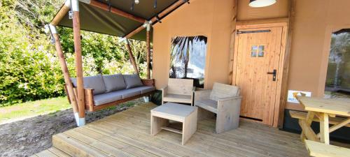 a porch of a house with a couch and a table at Luxe Safaritent Friesland in Grou