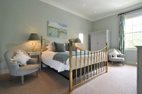 a bedroom with a bed and a chair and a crib at Congham Hall Hotel & Spa in Grimston