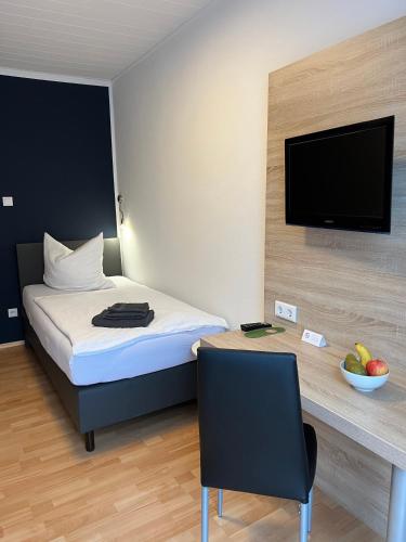 ein Hotelzimmer mit einem Bett und einem Schreibtisch mit einem TV in der Unterkunft Hotel Monopol in Hilden