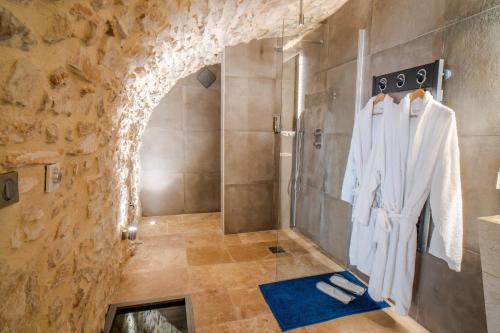 y baño con ducha en una pared de piedra. en Chambre d'hôte avec SPA privatif domaine les nuits envôutées - Gard, en Vézénobres