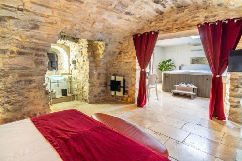 1 dormitorio con 1 cama grande en una pared de piedra en Chambre d'hôte romantique avec SPA privatif domaine les nuits envôutées - Vézénobres, en Vézénobres