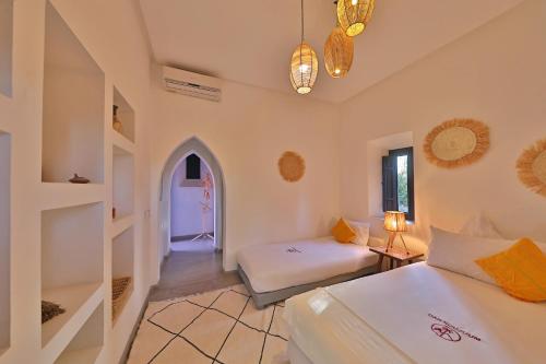 a bedroom with two beds and a room with a window at DAR NOUJOUM in Marrakech