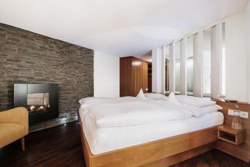 a bedroom with a large bed and a fireplace at Heimspitze - Alpenhotel & Wirtshaus in Gargellen