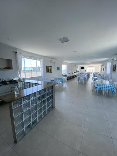 a large white room with tables and blue chairs at Hotel Real in Cabo Frio