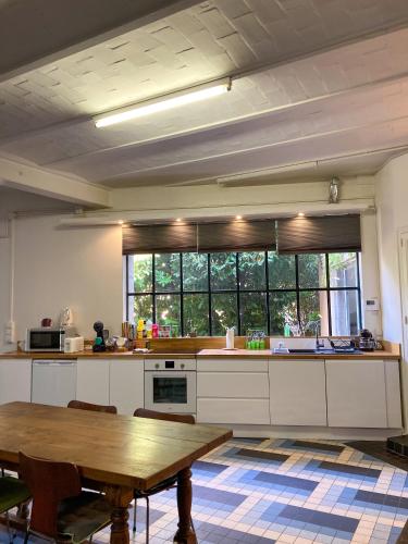 une cuisine avec une table en bois et une grande fenêtre dans l'établissement La Villa Victoria -Malzéville Village -120m2, à Nancy