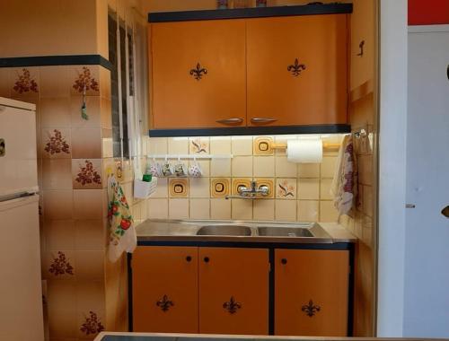 una cucina con armadi arancioni e lavandino di Μαγευτικο ηλιβασιλεμα Μαρμαρι Ευβοιας a Marmari