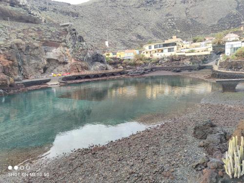 a pool of water on a rocky shore with houses at Mi Paraiso Vacacional, Isla del Hierro. in Tamaduste