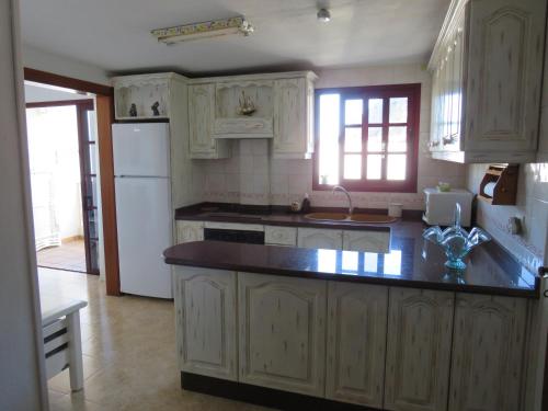 a kitchen with white cabinets and a black counter top at Mi Paraiso Vacacional, Isla del Hierro. in Tamaduste