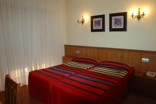 a bedroom with a bed with a red blanket on it at Hotel Santa Teresa in Avila