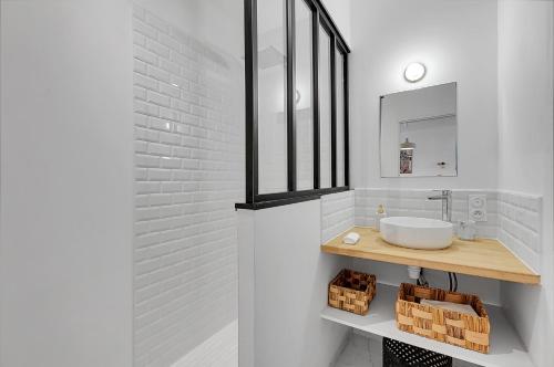 La salle de bains est pourvue d'un lavabo et d'un mur en briques blanches. dans l'établissement LA PARENTHÈSE - Charmant T2 entièrement rénové, à Toulouse
