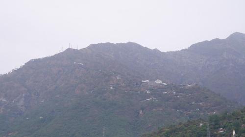 a mountain with trees and houses on top of it at Saatvik Homestay in Katra