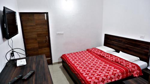 a bedroom with a bed and a desk and a television at Saatvik Homestay in Katra