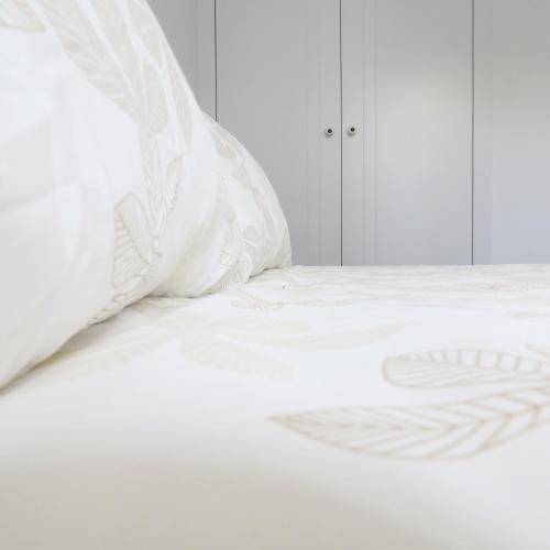 a white bed with white sheets and a pillow at Piso Virgen del mar in Laxe