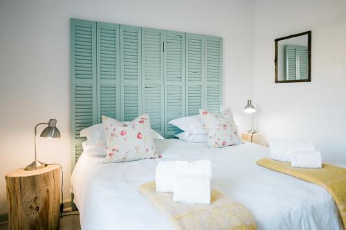 una camera con due grandi letti bianchi con cuscini di The River Bend Cottages a Graaff-Reinet