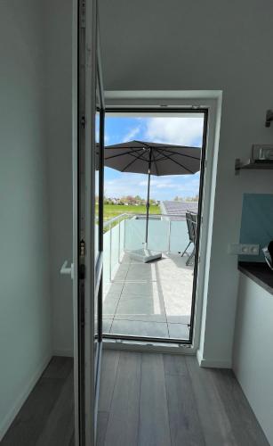 an open door to a balcony with an umbrella at Luv-Moderne Neubauwohnung in Strandnähe-Wallbox in Wremen