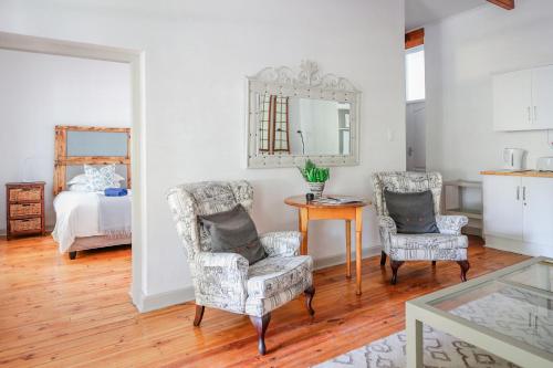 a living room with two chairs and a table and a bed at River Bend Guesthouses in Graaff-Reinet