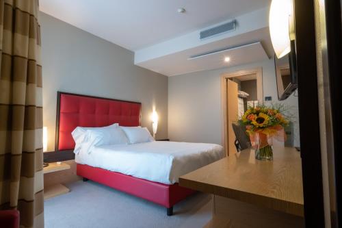 a hotel room with a bed with a red headboard at UNA HOTELS MH Matera in Matera
