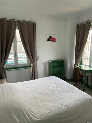 a bedroom with a bed and a table and windows at Le Lion d'Or in La Chaise-Dieu