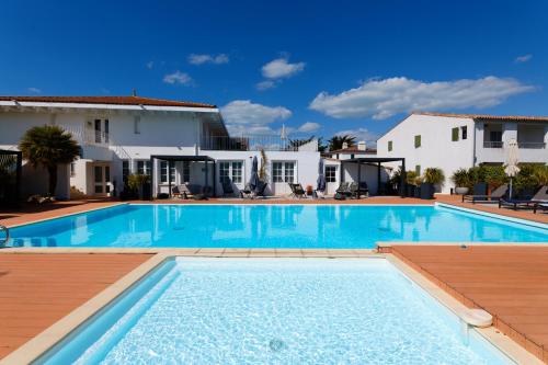 a swimming pool in front of a villa at HR Hôtel & Spa Marin in La Flotte