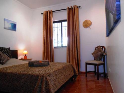a bedroom with a bed and a chair and a window at Villa Cabanas in Tavira