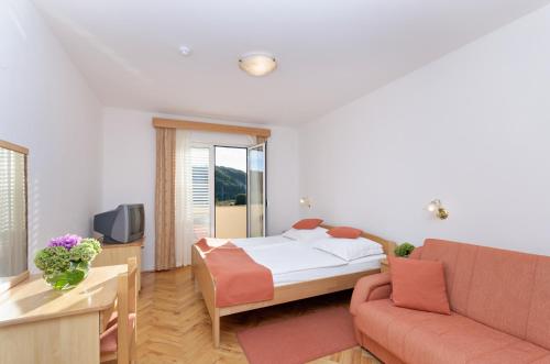 ein Hotelzimmer mit einem Bett und einem Sofa in der Unterkunft Hotel Epario in Rab