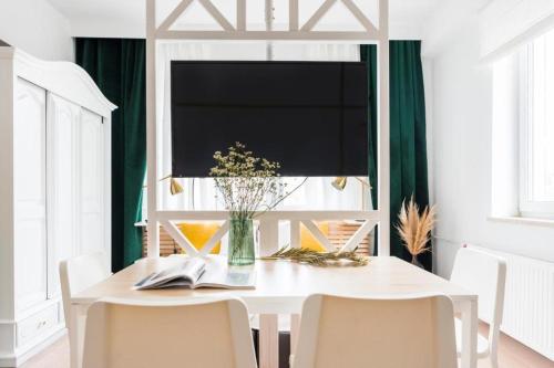 einen weißen Esstisch mit Stühlen und eine Vase aus Blumen in der Unterkunft Lux Apartment II in Danzig