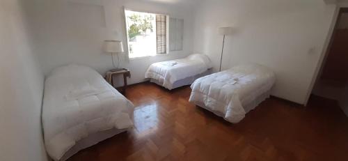 Habitación blanca con 2 camas y ventana en Casabella Bed & Breakfast en Mendoza