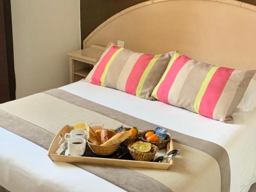 uma bandeja de comida em cima de uma cama em Hôtel de Flore em Saint-Raphaël