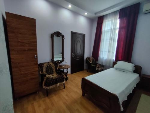 um quarto com uma cama, uma cadeira e um espelho em Guest House Nadejda em Batumi