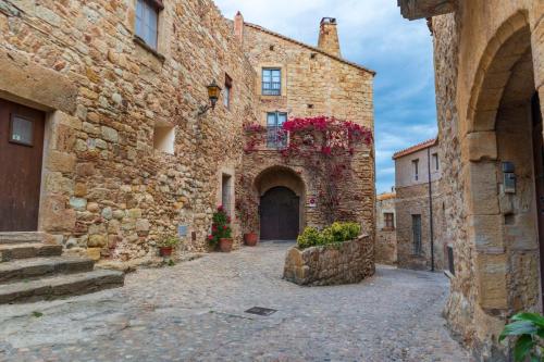 an alley in an old stone building with flowers at Can Costals Olivo in Pals