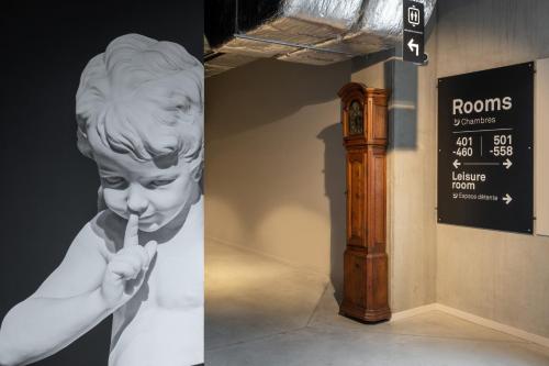a statue of a boy brushing his teeth next to a clock at ibis Styles Namur in Namur