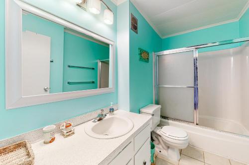 een badkamer met een wastafel, een toilet en een spiegel bij Bayside Beauty in Ocean City