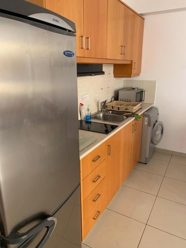 a kitchen with a stainless steel refrigerator and a sink at VIP Resort Apartment on Makenzie Beach in Larnaca