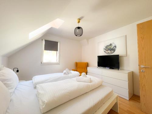 - une chambre blanche avec 2 lits et une télévision dans l'établissement Ferienwohnung im Zentrum von Kaltern, à Caldaro