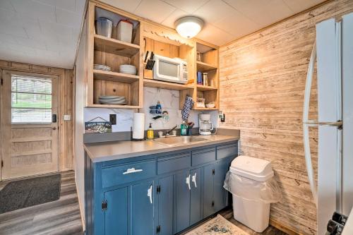 a kitchen with blue cabinets and a sink and a refrigerator at Quaint Table Rock Lake Hideout with Pool Access in Reeds Spring