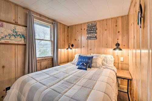 a bedroom with a bed with wooden walls and a window at Quaint Table Rock Lake Hideout with Pool Access in Reeds Spring