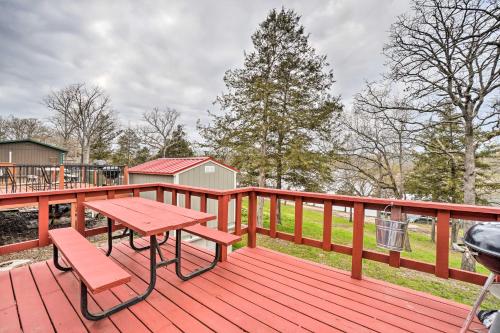 a wooden deck with a picnic table and a grill at Quaint Table Rock Lake Hideout with Pool Access in Reeds Spring