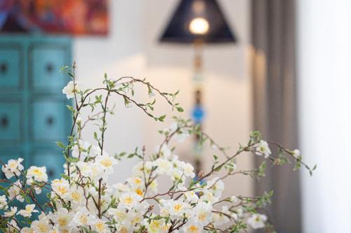 a vase filled with white flowers next to a lamp at Suite della Pigna in Rome