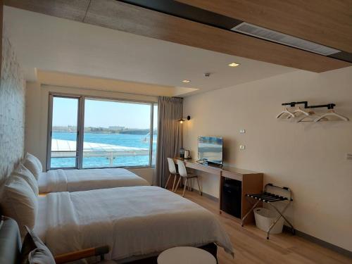 馬公市的住宿－麗詩旅海景民宿，一间卧室设有两张床、一张桌子和一个窗口。