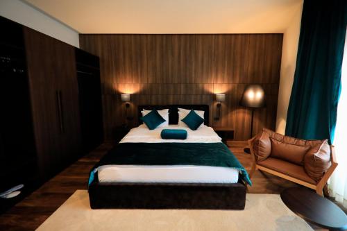 a bedroom with a large bed and a chair at Premium Park Hotel in Prizren