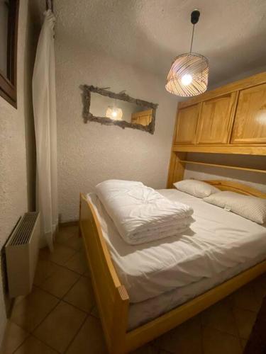 1 dormitorio con cama con sábanas blancas y luz en Laye station -les Arolles b - 4 personnes en Laye