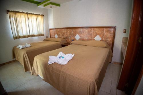 two beds in a hotel room with towels on them at Hotel Nicte-Ha in Campeche